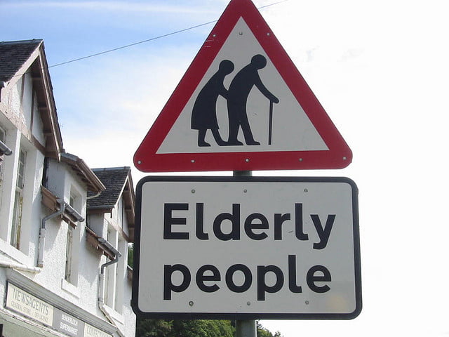 A triangular road sign warning drivers about elderly people crossing, with a rectangular sign below stating "Elderly people."