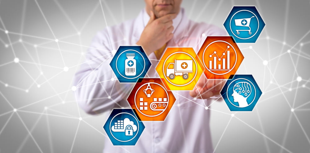 A man in a lab coat interacts with six hexagonal icons representing the pharmaceutical supply chain, including a prescription bottle, delivery truck, analytics, AI, data security, and manufacturing.