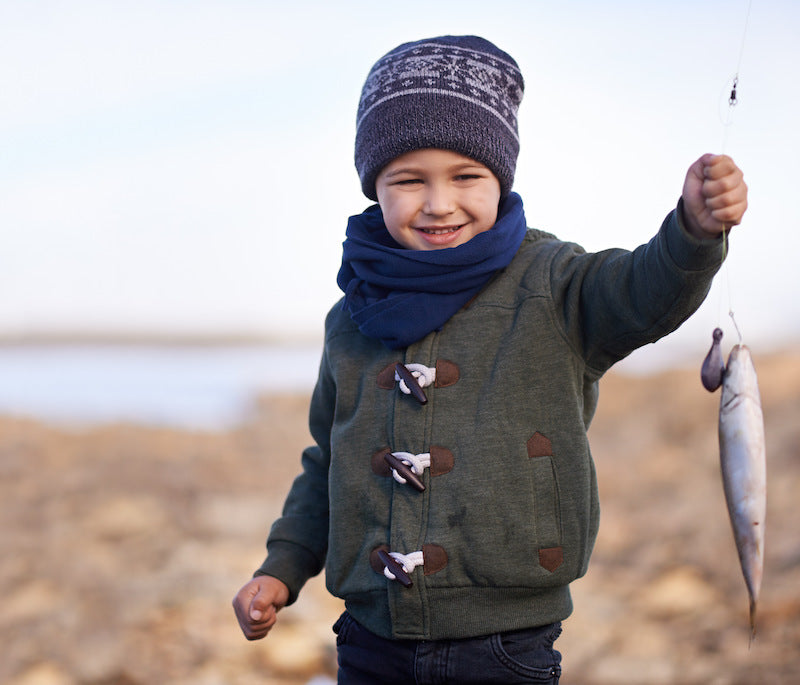 Child holding a fish on a fishing line with a blurred natural background