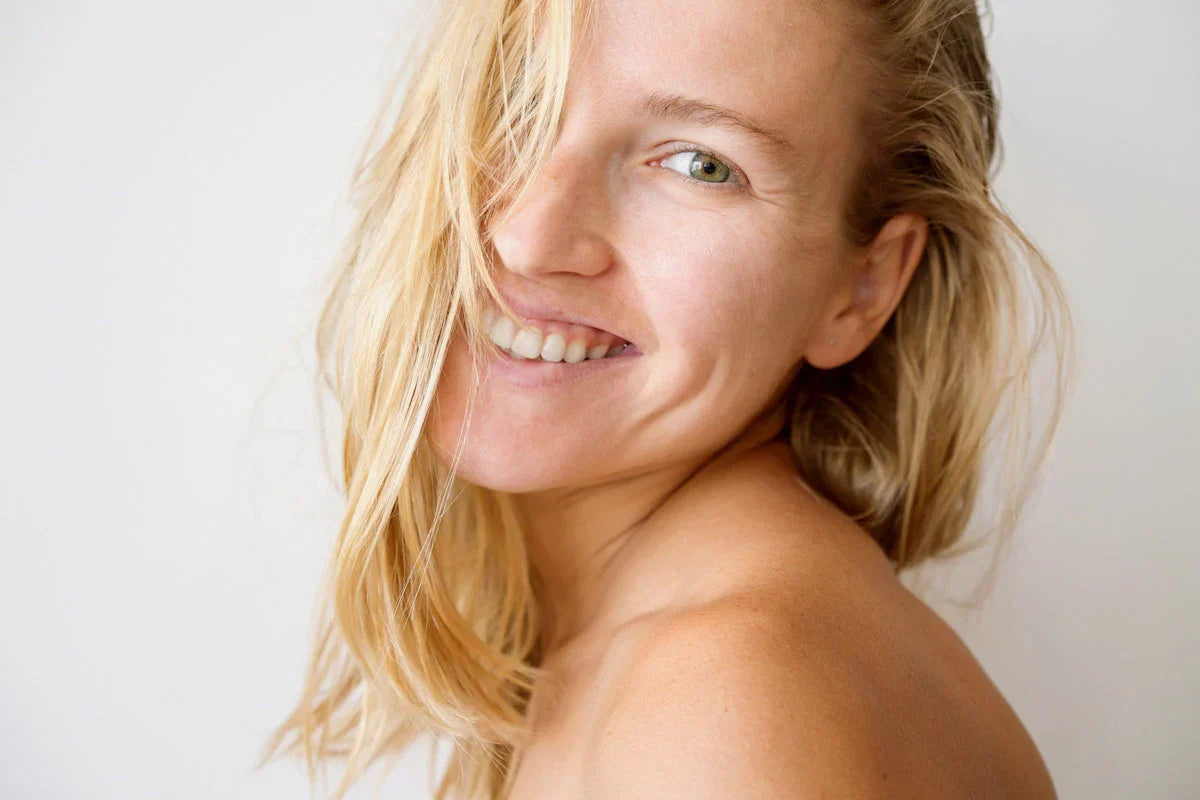 Woman with blonde hair smiling against a white background