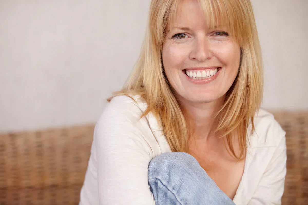 Woman with blonde hair and a white shirt sitting on a couch.