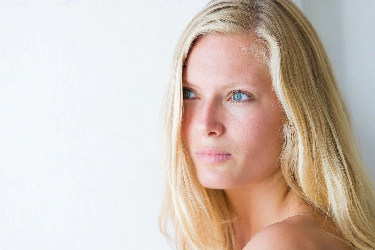 Woman with blonde hair and blue eyes against a white background